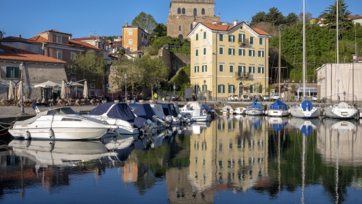 un'immagine della pittoresca cittadina, Muggia. Con le sue case colorate, il castello e il porticciolo a ridosso degli edifici.  Foto di P. Benini