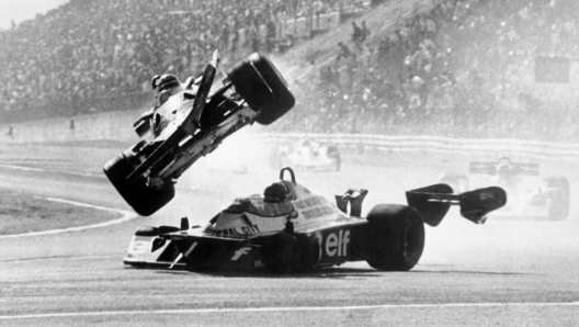 An unlocated photo taken in 1974 shows Gilles Villeneuve (C) of Canada being interviewed in his car as his son Jacques (R) stands by. (Photo credit should read AFP/AFP via Getty Images)