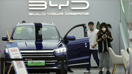 People visit a Chinese automaker BYD store on Wednesday, March 16, 2022, in Beijing. China's government tried Wednesday to reassure jittery investors by promising support for its struggling real estate industry, internet companies and entrepreneurs after regulatory crackdowns caused stock prices to plunge. (AP Photo/Ng Han Guan)