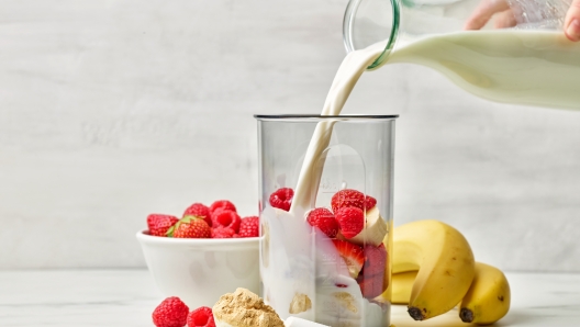 fresh milk pouring into blender container for making healthy breakfast milkshake