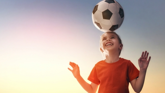 Cute little child dreams of becoming a soccer player. Girl plays football.