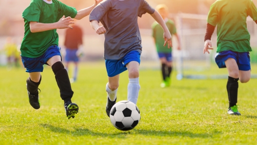 Bambini che d'estate corrono dietro al pallone