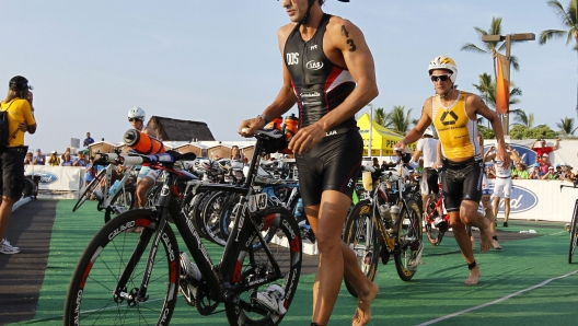 epa02956839 Daniel Fontana of Italy races through the transition area to begin the 112 mile biking leg of the Ironman World Championship 2011 at the Kailua Bay in Kailua-Kona, Hawaii, USA, 08 October 2011. The triathletes go through a 2.4 mile swim, followed by a 112 mile bike ride and a 26.2 mile marathon.  EPA/BRUCE OMORI