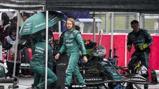 epa10232187 German Formula One driver Sebastian Vettel (C) of Aston Martin walks by his car in the pitlane as the race is stopped due to heavy rain during the Formula One Grand Prix of Japan at the Suzuka International Racing Course, Suzuka, Japan, 09 October 2022.  EPA/TORU HANAI / POOL