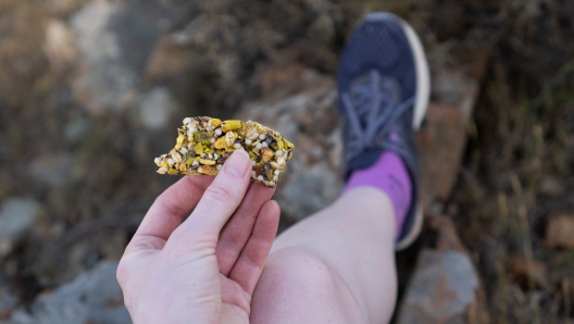 Sweet healthy and hearty food. Hand holding fitness bar. Healthy sweets for runners. Bar of nuts and honey for hiking. High quality photo