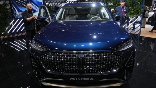 Visitors watch the WEY Coffeee 01 plug-in Hybrid SUV by Chinese automaker Great Wall Motors at the Paris Car Show Monday, Oct. 17, 2022 in Paris. Europe is leading the charge into electric vehicles as battery powered cars break out of their niche market of first adopters and enter the mainstream with increasing market share that's forecast to grow strongly as the EU pushes to phase out internal combustion engine vehicles by 2035 (AP Photo/Michel Euler)