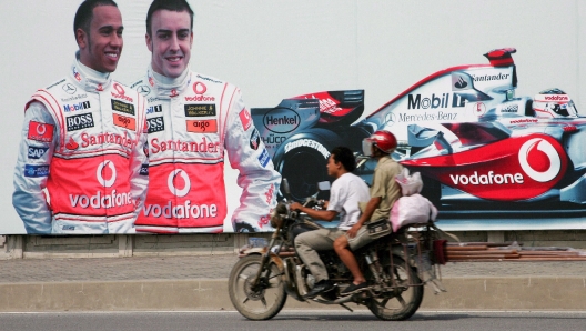 epa01138288 A motorbike passes in front of a giant poster of Spanish Formula One driver Fernando Alonso and his British teammate Lewis Hamilton of McLaren Mercedes 04 October 2007 in Shanghai, China. The Chinese Formula One Grand Prix will take place at Shanghai International Circuit 05 October 2007.  EPA/GERO BRELOER BASIS