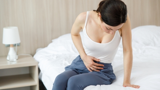 Cystitis in a woman. A young woman has a pain in the lower abdomen, she holds her stomach with her hand