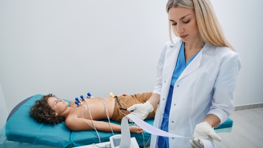 Pediatrician looking ECG printout of child patient after heart electrocardiogram procedure at medical clinic