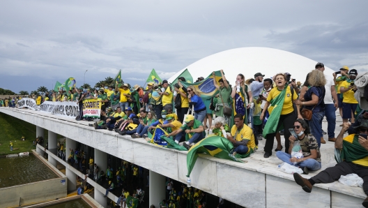 Protesters, supporters of Brazil's former President Jair Bolsonaro, stand on the roof of the National Congress building after they stormed it, in Brasilia, Brazil, Sunday, Jan. 8, 2023. (AP Photo/Eraldo Peres)