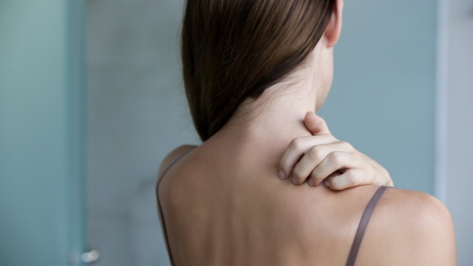 Close up view of woman scratching her neck.