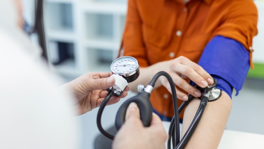 Doctor using sphygmomanometer with stethoscope checking blood pressure to a patient in the hospital.