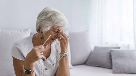 Elderly woman suffering from headache at home. Close up aged woman with headache. Health care, pain, stress, age and people concept