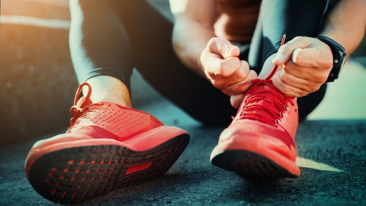 Man tying jogging shoes.He is running outdoors on a sunny day.