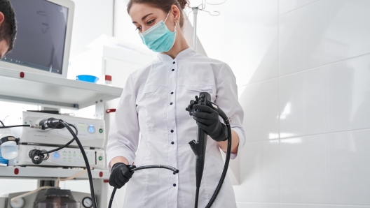 Waist up portrait view of the female doctor gastroenterologist with probe to perform gastroscopy and colonoscopy. Gastroscopy concept