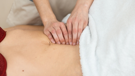 Top view of an unrecognizazble physiotherapist checking diastasis recti on belly of postpartum woman.