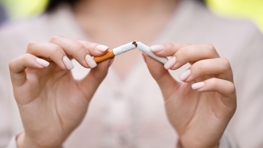 Stop smoking concept. Unrecognizable woman breaking cigarette outdoors, closeup image with selective focus