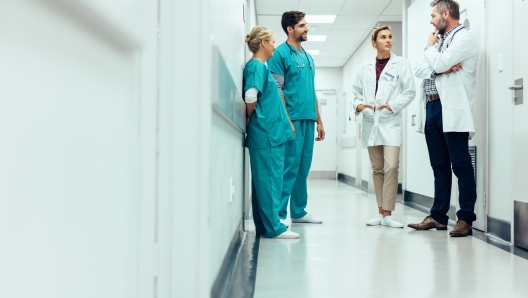 Group of medical staff discussing in clinic hallway. Healthcare professionals having discussion in hospital corridor.