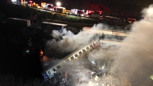 Smoke rises from trains as firefighters and rescuers operate after a collision near Larissa city, Greece, early Wednesday, March 1, 2023. The collision between a freight and passenger train occurred near Tempe, some 380 kilometers (235 miles) north of Athens, and resulted in the derailment of several train cars. (AP Photo/Vaggelis Kousioras)