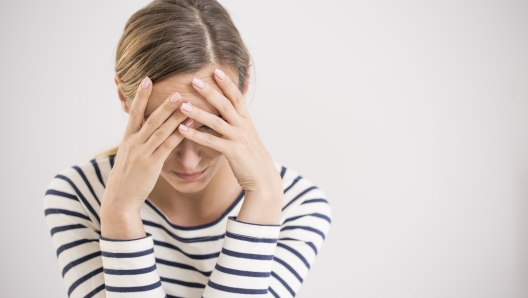 Young hopeless woman suffering from depression having nervous breakdown holding her head on isolated background, copy space