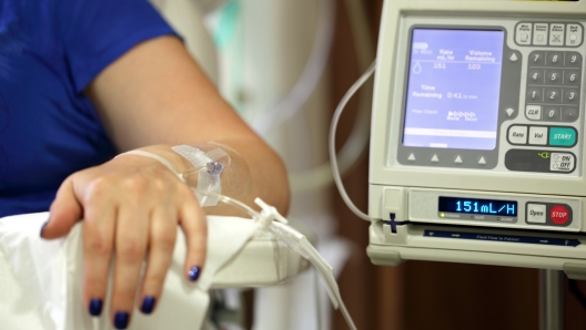 Infusion pump feeding IV drip into patients arm focus on needle