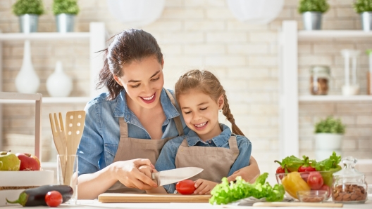 Healthy food at home. Happy family in the kitchen. Mother and child daughter are preparing the vegetables and fruit.