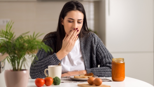 Young woman feeling nausea during breakfast time at home