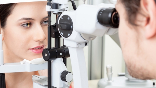 High technology concept health for eyes care - The optician ophthalmology doctor optometrist in the eyes clinic using a binocular slit-lamp to a young woman for an eye control