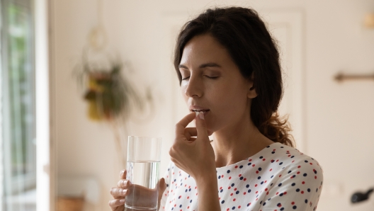 Stressed tired woman taking vitamins, painkillers, antidepressants, pills, meds against headache, insomnia, nervous disorder, anxiety. Patient with medication fighting against flu infection, migraine