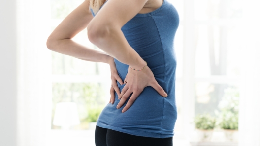 Young sporty woman touching her lower back, she feels pain