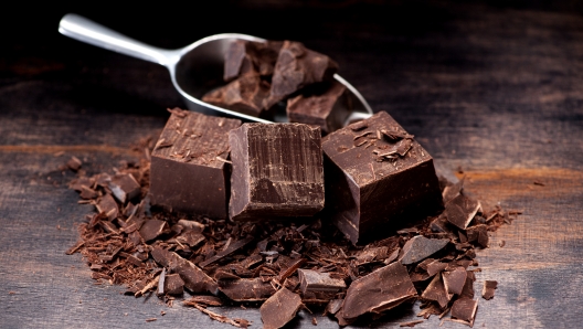 Dark chocolate in a metal scoop and on a table