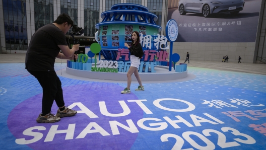 Attendees film the Auto Shanghai 2023 at the National Exhibition and Convention Center in Shanghai, China, Tuesday, April 18, 2023. Global and Chinese automakers plan to unveil more than a dozen new electric SUVs, sedans and muscle cars this week at the Shanghai auto show, their first full-scale sales event in four years in a market that has become a workshop for developing electrics, self-driving cars and other technology. (AP Photo/Ng Han Guan)