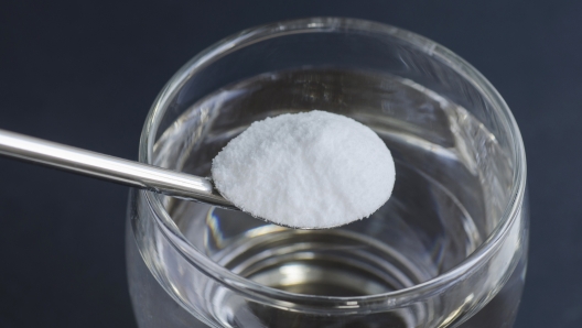 Spoon of baking soda over glass of water