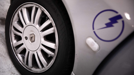 This photograph taken on January 26, 2023, shows a Renault logo on a hubcar of a Twingo car and an electric power logo on the side panel, at the Lormauto company, in Hermival-les-vaux, near Lisieux, northwestern France. - Lormauto company works on removing the combustion engines from Twingo and converting them into electric vehicles. (Photo by Lou BENOIST / AFP)