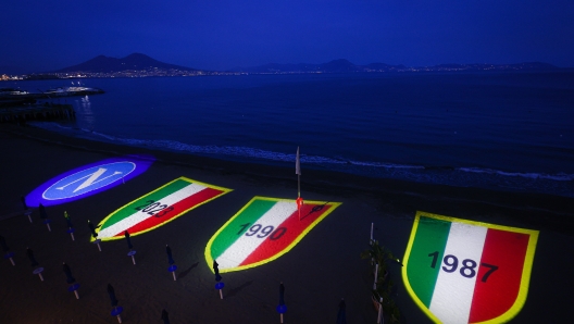 Foto Alessandro Garofalo/LaPresse 27-04-2023 Napoli, Italia Napoli Campione d?Italia nella foto la suggestiva proiezione dei tre scudetti sulla spiaggia di Posillipo sullo sfondo il Vesuvio singolo della città   April 27, 2023  Naples, Italy News Naples Campione d'Italia in the photo the suggestive projection of the three badges on the beach of Posillipo in the background the single Vesuvius of the city