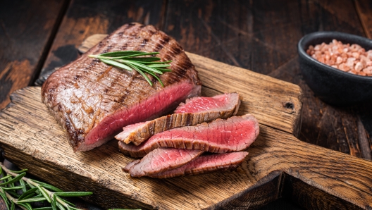 Barbecue dry aged wagyu Flank Steak on a cutting board. Wooden background. Top view.