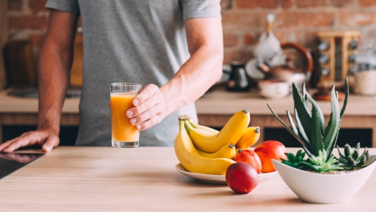 Healthy habit. Balanced diet and nutrition. Cropped shot of man holding fresh fruit juice glass. Organic banana, nectarine drink.