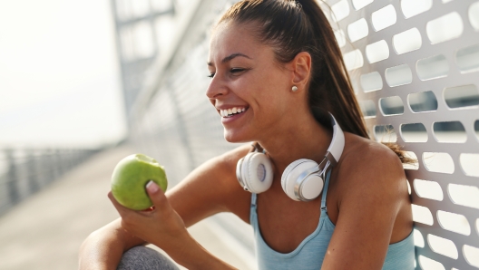 Beautiful girl making a break to eat apple while sitting on the ground.