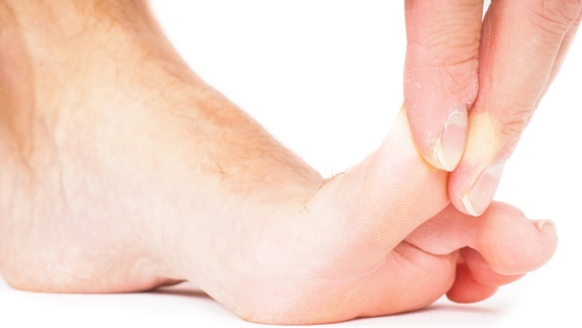 Male person pulling big toe backwards isolated towards white