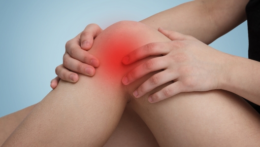 woman sitting with her hands around the knee on one of the legs. on a blue background