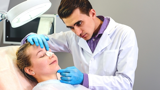 Male doctor preparing a mold of the curve of the nose the patient is female, to follow the alignment procedure of the nose. Rena Therme Hartman for plastic surgery.