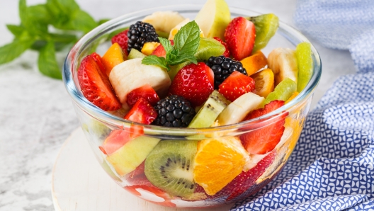 Healthy fresh fruit salad in a bowl on a gray background.