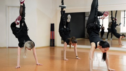 Close-up group of girls hanging on bungee rubber bands in the gym. Girls perform a difficult exercise with bungee gum