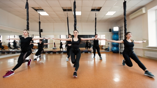 Group of active sports girls in black sportswear are engaged in budgie fitness in the gym. Bungee jumping in the gym