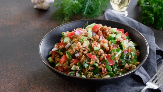 Whole Grain spelt salad with seasonal vegetables on dark background. Close up. Space for text.