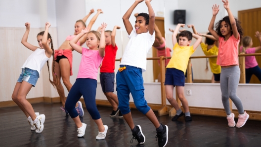 Group of happy tweens with female teacher practicing hip hop in modern dance studio