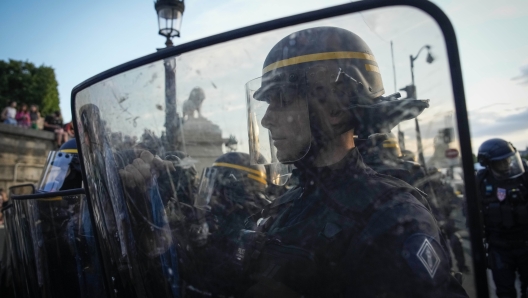 Police officers stand guard in front of protesters on Concorde square during a protest in Paris, France, Friday, June 30, 2023. French President Emmanuel Macron urged parents Friday to keep teenagers at home and proposed restrictions on social media to quell rioting spreading across France over the fatal police shooting of a 17-year-old driver. (AP Photo/Lewis Joly)