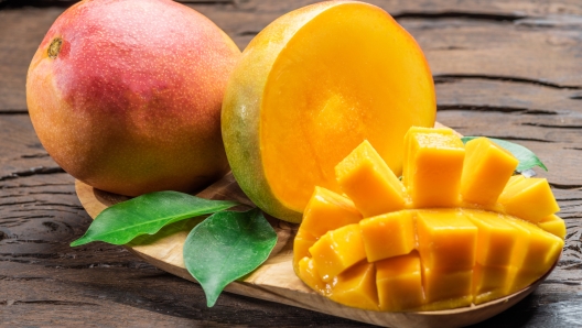 Mango fruits and mango slices on the old wooden table.