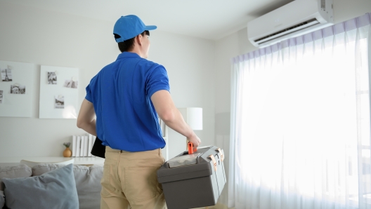 An Asian young Technician service man wearing blue uniform checking ,  cleaning air conditioner in home