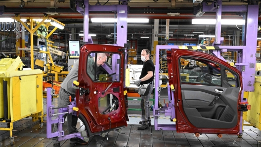 Employees work on a production line at the MCA plant in Maubeuge, northern France, on October 6, 2022. - The MCA plant (Maubeuge Construction Automobile) will produce the Renault 4L and Renault Scenic in the northern region of Hauts-de-France. (Photo by FRANCOIS LO PRESTI / AFP)